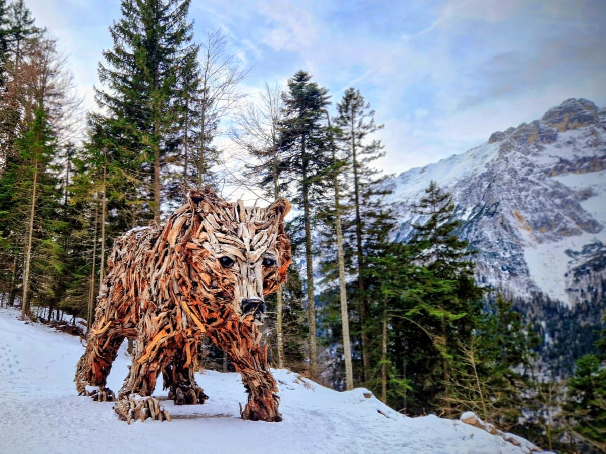 Scultura in legno di un orso su un sentiero innevato vicino a Molveno